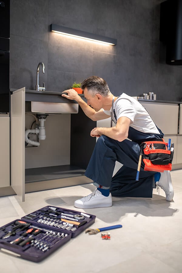man-kneeling-down-touching-sink-inspecting-pipes-2023-11-27-05-20-45-utc (1)